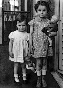 zwei kleine Mädchen mit Puppe im Arm